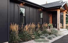 a house that has some plants in front of it and grass on the ground outside