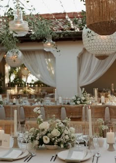 the table is set with white flowers and place settings for an elegant dinner or reception