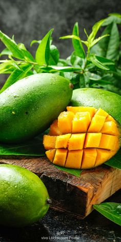 mangoes and avocados cut in half on a cutting board next to leaves