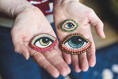 two people holding their hands with beaded eye rings on each hand and one has an eye ring in the middle