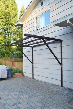 an outdoor dining area with table and chairs in front of a house on a brick patio