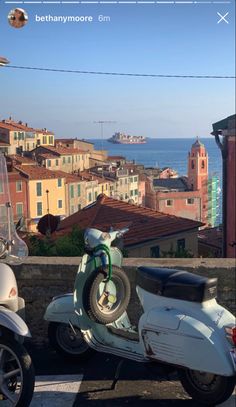 two scooters are parked next to each other in front of some buildings and the ocean