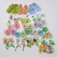 a bunch of different colored flowers on a white surface with beads and string attached to them