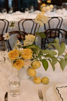 an arrangement of flowers and lemons on a table in a restaurant or dining room