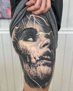 a man's leg with tattoos on it and his face painted in black and white