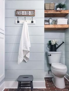 a white toilet sitting next to a wooden shelf