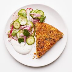 a white plate topped with a slice of pizza next to a pile of veggies