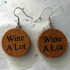 two wine cork earrings with the words wine alot written in black ink on them