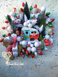 a wreath made out of balloons and christmas decorations on the ground with a camper in the background