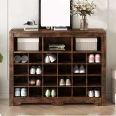 a wooden shelf filled with shoes next to a vase and tv on top of it