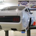 a white mustang car on a lift in a garage