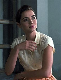 a woman sitting on top of a bed next to a window