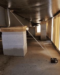 the inside of an empty building with concrete blocks on the ground and metal pipes attached to the ceiling