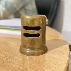 a wooden table with a small metal object on it's top and a person in the background