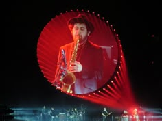 a man that is standing up with a saxophone in his hand and lights on behind him