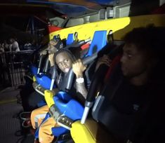 two people sitting in a roller coaster at an amusement park, one person is holding the steering wheel