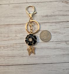 a gold keychain with a black flower on it and a coin sitting next to it