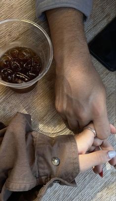 two people sitting at a table holding hands over a small glass bowl with jelly in it