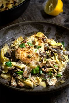 a close up of a plate of food with chicken and mushrooms on it next to a lemon wedge