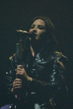 a woman with long hair holding a microphone in her hand and singing into the microphone