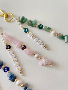 several beads and charms are arranged on a white surface with a gold keychain