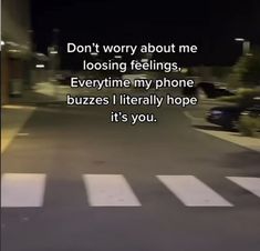 a person walking across a street at night with the words don't worry about me loosing feelings