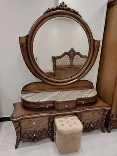 an ornate wooden dresser with mirror and foot stool