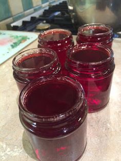 four jars filled with red liquid sitting on top of a counter