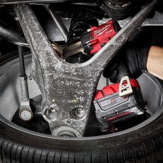 a man is working on the front wheel of a car with tools in his hand