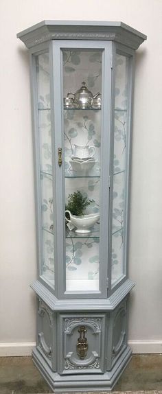 an old china cabinet with glass doors and silver trimmings on the top shelf