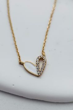 This dainty Tiny Heart Necklace features a delicate gold and white accent adorned with tiny rhinestones. The delicate chain includes an extender for a customizable fit. Elevate any outfit with this elegant and timeless piece. Length: 16" Extender Chain: 2" Finish: Gold Plating Product: Cubic Zirconia White Heart Clavicle Chain Necklace For Anniversary, White Clavicle Chain Heart Necklace For Anniversary, White Heart Necklace With Chain, Anniversary White Heart Clavicle Necklace, Dainty White Charm Necklaces With Heart Pendant, White Charm Necklace With Adjustable Chain For Anniversary, White Clavicle Chain Necklace With Open Heart, Dainty White Necklace With Adjustable Chain, Dainty White Chain Necklace For Anniversary