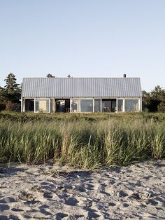 the house is surrounded by tall grass and sand