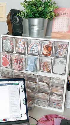 a laptop computer sitting on top of a desk next to a shelf filled with magnets