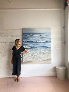 a woman standing in front of a painting on the wall