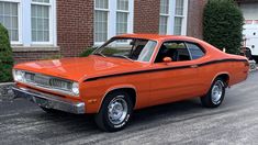 an orange car parked in front of a brick building