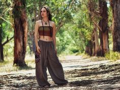 a woman standing in the middle of a forest wearing a crop top and wide legged pants