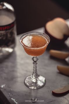 an apple martini sits on a table next to sliced apples