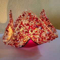 a red vase sitting on top of a table covered in lots of small beads and stones