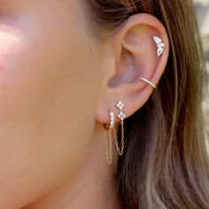 a close up of a person wearing gold ear cuffs with diamonds on the end and chain attached to them