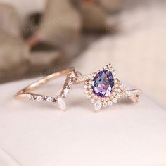 a ring with an amethorate and diamonds on it sitting on top of a pillow