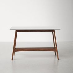 a white table sitting on top of a cement floor next to a wooden frame and shelf