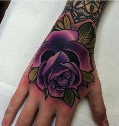 a person's hand with a tattoo on it and a purple rose in the middle