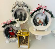 three christmas decorations are on display in front of a white wall and two small tables