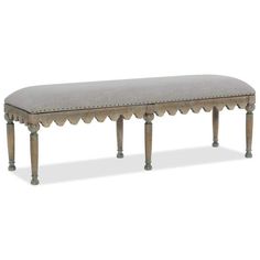 an upholstered bench with scalloped legs and a gray fabric seat cover