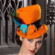 a woman wearing an orange hat with feathers on it