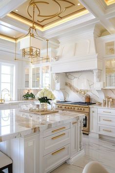 a large kitchen with marble counter tops and gold accents on the ceiling, along with white cabinets