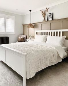 a white bed sitting in a bedroom next to a window with shutters on both sides