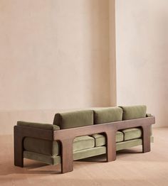 a green couch sitting on top of a hard wood floor next to a white wall