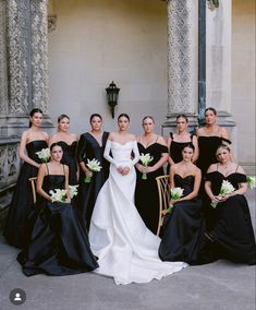 a group of women standing next to each other in black dresses and holding bouquets