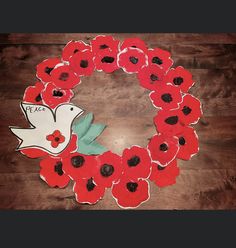 a wreath with red poppies and a white dove on it sitting on a wooden floor